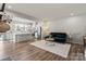 Bright, open-concept living room featuring hardwood floors, modern furniture, and a view of the kitchen and bar seating at 15622 Little Bluestem St, Charlotte, NC 28278