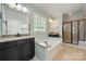Bright bathroom featuring a tub with tile, shower, granite counters, and dark cabinets at 199 Blossom Ridge Dr, Mooresville, NC 28117
