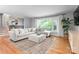 Bright and airy living room with a large sectional couch, hardwood floors, and a view of mature trees at 2009 Edgewater Dr, Charlotte, NC 28210