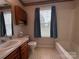 Bathroom with laminate countertops, wood vanity, and window with blinds and curtains at 2504 Faircroft Way, Monroe, NC 28110
