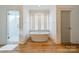 Bright bathroom features a soaking tub, a marble shower, and a window for natural light on hardwood floors at 331 Anthony Cir, Charlotte, NC 28211