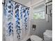 Bathroom features a shower with decorative blue shower curtain, toilet, and window at 500 Colony Acres Dr, Charlotte, NC 28217