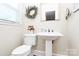 Neat powder room with a pedestal sink, toilet, and decorative accents at 704 Kingman Dr, Charlotte, NC 28217