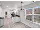 Modern kitchen with white cabinets, black hardware, plank flooring and eat-in area with ample natural light at 8027 Bristle Ln, Charlotte, NC 28214