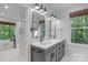 Elegant bathroom with dual sink vanity, stylish mirrors, modern lighting fixtures and a separate tub and shower area at 8400 Prince Valiant Dr, Waxhaw, NC 28173