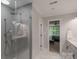 Hallway view of the updated bathroom with glass shower, modern fixtures, and access to the Primary bedroom at 8400 Prince Valiant Dr, Waxhaw, NC 28173