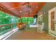 Covered deck features outdoor seating, wood flooring, ceiling fans, and a view of a wooded backyard at 8400 Prince Valiant Dr, Waxhaw, NC 28173