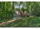 Scenic view of a home in the woods with a large green lawn and brick walkway at 8400 Prince Valiant Dr, Waxhaw, NC 28173