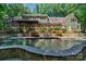 View of a large pool and stone patio area that backs up to the house with lots of shrubbery and foliage at 8400 Prince Valiant Dr, Waxhaw, NC 28173