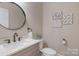 Stylish powder room with a round mirror, updated vanity, marble countertop, and modern fixtures at 8400 Prince Valiant Dr, Waxhaw, NC 28173