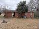 Brick home's backyard featuring a covered patio, ample space, and a large tree providing shade at 910 Mcgowan Rd, Shelby, NC 28150