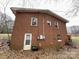 Rear exterior view of a brick home, highlighting its structure, door, and windows in natural light at 910 Mcgowan Rd, Shelby, NC 28150