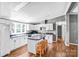 Spacious kitchen features white cabinets, dark countertops, a center island with seating, and hardwood flooring at 10230 Hagers Rd, Huntersville, NC 28078