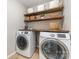 Functional laundry room with washer, dryer, and open shelving for storage at 11014 Aspen Ridge Nw Ln, Concord, NC 28027