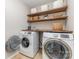 Bright laundry room featuring modern appliances and wooden shelving for organization at 11014 Aspen Ridge Nw Ln, Concord, NC 28027