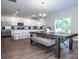 Bright dining area with a large window, modern chandelier, gray wood flooring, and a modern table with bench seating at 112 Tanner Loop, Troutman, NC 28166