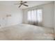 Bedroom with neutral carpeting and paint features a ceiling fan and a window with sheer curtains at 1205 Southwood Dr, Newton, NC 28658