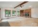 Open living room features a stone fireplace, ceiling beam and large picture windows looking out to the yard at 1205 Southwood Dr, Newton, NC 28658