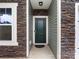 Close-up of a home's front door with stone accents, green siding, and a modern light fixture at 1523 Loropetalum Rd, Charlotte, NC 28215