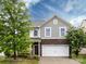 Charming two-story home with stone accents, a well-manicured lawn, mature trees, and a two-car garage at 1523 Loropetalum Rd, Charlotte, NC 28215
