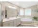 Bright bathroom featuring double sinks, a soaking tub, and windows for natural light at 1542 Crowders Woods Dr, Gastonia, NC 28052