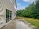 View of concrete back patio with sliding glass door and wooded backyard in this home at 15923 Prescott Hill Ave, Charlotte, NC 28277