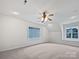 Bright bedroom with plush carpet, modern ceiling fan, and plenty of light from the windows at 15923 Prescott Hill Ave, Charlotte, NC 28277
