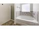 Modern bathroom featuring a soaking tub with mosaic tile surround and glass-enclosed shower at 2713 Reid Meadows Dr, Charlotte, NC 28208