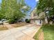 Beautiful two-story home with stone accents, vinyl siding, mature trees, and a long concrete driveway at 2713 Reid Meadows Dr, Charlotte, NC 28208