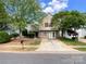 Charming two-story home with stone accents, vinyl siding, mature trees, and a long concrete driveway at 2713 Reid Meadows Dr, Charlotte, NC 28208