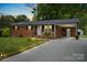 Charming brick home featuring a well-maintained lawn and a covered carport area at 324 Autumn Dr, Harrisburg, NC 28075