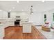 Modern kitchen with white cabinetry, stainless steel appliances, and hardwood floors, adjacent to a seating area at 3610 Mill Pond Rd, Charlotte, NC 28226