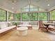 Bright sunroom featuring large windows, ample seating, and a view of the surrounding trees at 3610 Mill Pond Rd, Charlotte, NC 28226