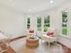 Bright sitting area with hardwood floors, white chairs with red pillows, and natural light streaming in through the windows at 3610 Mill Pond Rd, Charlotte, NC 28226