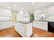 A well-lit kitchen with white cabinets, an island, granite countertops, and hardwood floors at 415 Princeton Dr, Salisbury, NC 28144
