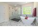 Bright bathroom with a luxurious soaking tub, separate glass shower, and elegant marble tile at 424 Preston Rd, Mooresville, NC 28117