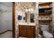 Classic bathroom featuring wood-grain cabinets, floral wallpaper, and storage shelves at 480 S Ingleside Farm Rd, Iron Station, NC 28080
