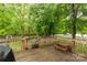 An open wooden back deck, surrounded by lush greenery, has a quaint picnic table and leads to a fenced backyard at 522 Kittiewake Ln, Clover, SC 29710