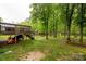 A backyard oasis with mature trees, an elevated deck, and play equipment offers a blend of relaxation and recreation at 522 Kittiewake Ln, Clover, SC 29710