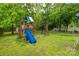 A wooden playground with a slide and swings sits in the expansive backyard, surrounded by mature trees and green grass at 522 Kittiewake Ln, Clover, SC 29710