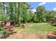 Expansive backyard with a lush green lawn, a shed, and a variety of beautiful trees and plants at 530 Bonita Dr, Landis, NC 28088