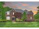 Charming brick home featuring manicured landscaping, a gray roof, and a double door entry at 5940 Four Wood Dr, Matthews, NC 28104