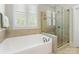 Bathroom featuring a soaking tub with a shower enclosed by glass and a window at 601 Dorothy Dr, Charlotte, NC 28203