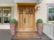 Elegant wood front door with glass panels flanked by potted plants, welcome mat, and siding at 601 Dorothy Dr, Charlotte, NC 28203