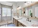 Bright main bathroom featuring double sink vanity, framed mirrors and tiled walk-in shower at 7814 Knox Ridge Rd, Huntersville, NC 28078