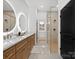 Modern bathroom with dual sinks, wood cabinets, glass shower, and white tile floors at 8044 Edgewater Dr # 100, Norwood, NC 28128