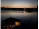 An after dark lake view shows a boathouse with lights creating an inviting and picturesque waterside scene at 8044 Edgewater Dr # 100, Norwood, NC 28128