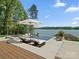 Luxury pool overlooking the lake featuring lounge seating, an umbrella, and mature trees at 8044 Edgewater Dr # 100, Norwood, NC 28128