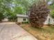 Charming house featuring a long driveway, mature trees, and a well-maintained lawn and garden at 8600 Eaglewind Dr, Charlotte, NC 28212