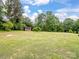 Expansive grassy backyard featuring mature trees and shed for storage and outdoor enjoyment at 895 Furnace Rd, Iron Station, NC 28080